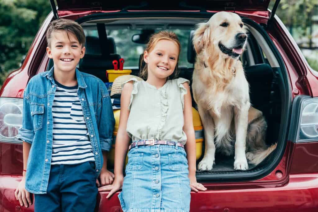 adorable little kids with dog in car trunk